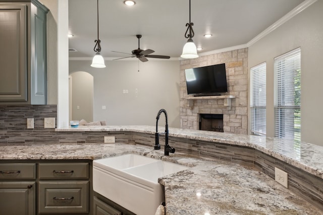 kitchen with sink, a fireplace, pendant lighting, ceiling fan, and ornamental molding