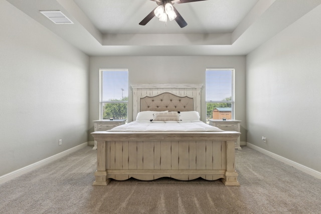 bedroom with carpet floors, ceiling fan, and a tray ceiling