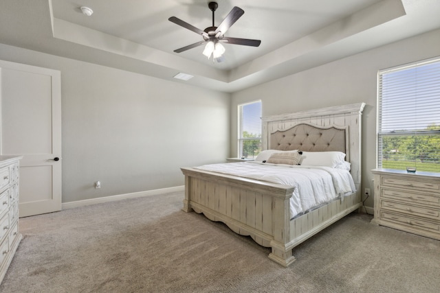 carpeted bedroom featuring ceiling fan and a tray ceiling