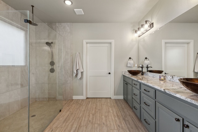 bathroom featuring a tile shower, hardwood / wood-style flooring, and double vanity