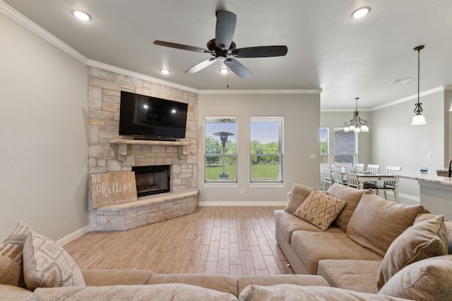 living room with ceiling fan with notable chandelier, light hardwood / wood-style floors, crown molding, and a fireplace