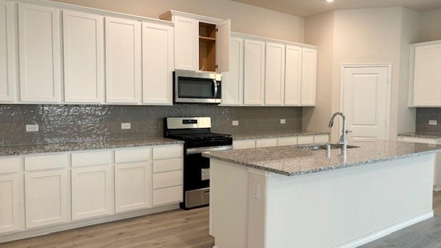 kitchen featuring light wood-type flooring, appliances with stainless steel finishes, decorative backsplash, and a sink