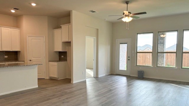 kitchen featuring plenty of natural light, ceiling fan, wood-type flooring, and white cabinetry