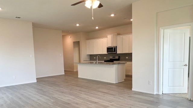 kitchen with ceiling fan, stainless steel appliances, light hardwood / wood-style floors, and a kitchen island with sink