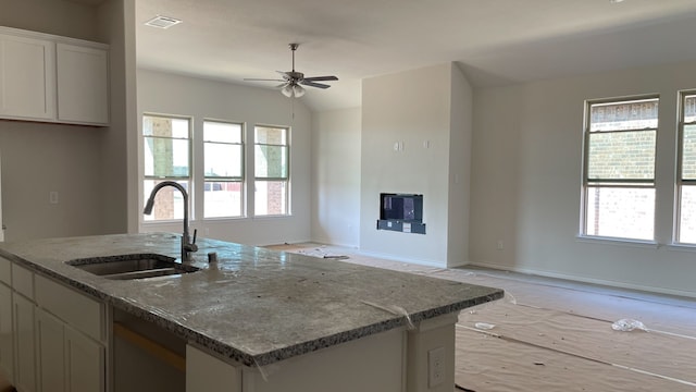 kitchen featuring stone countertops, a wealth of natural light, sink, and ceiling fan