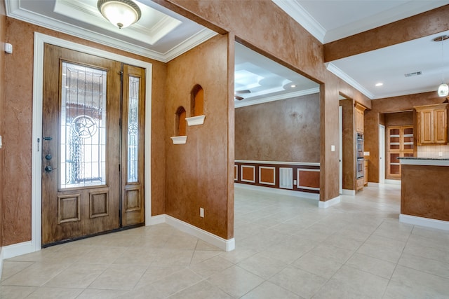 foyer featuring a raised ceiling, ornamental molding, and light tile patterned floors