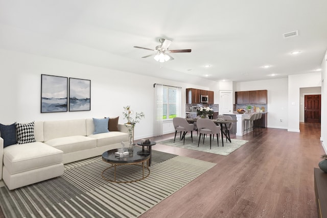 living room with dark wood-type flooring and ceiling fan