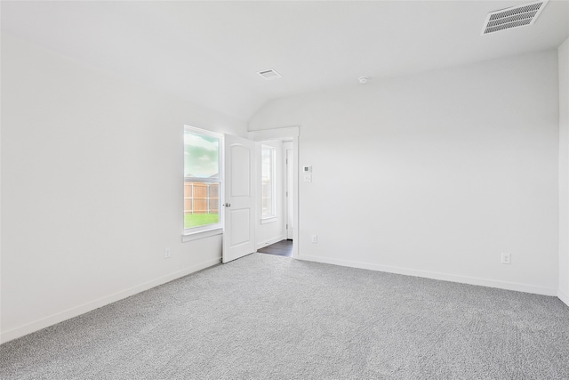 carpeted spare room with vaulted ceiling