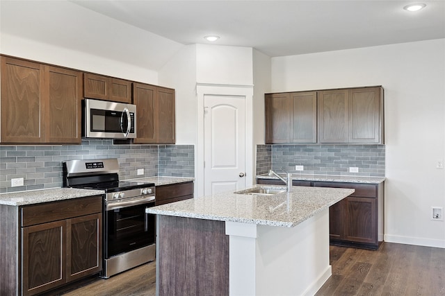 kitchen featuring stainless steel appliances, sink, an island with sink, and dark hardwood / wood-style floors