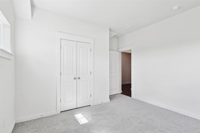 unfurnished bedroom featuring a closet and light colored carpet