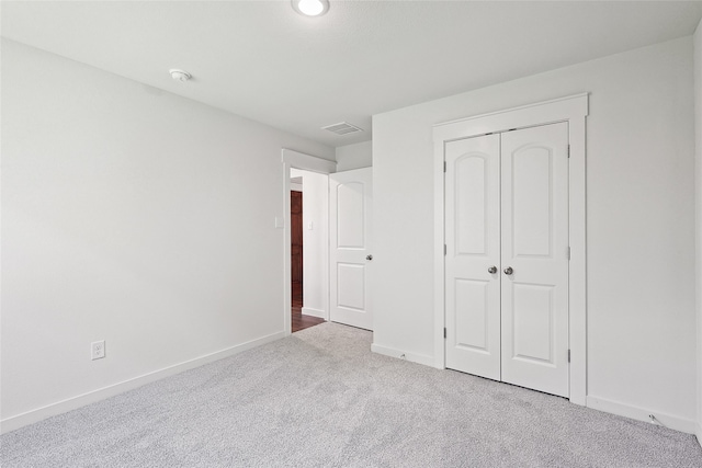 unfurnished bedroom featuring light carpet and a closet