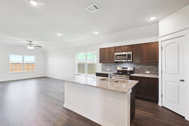 kitchen with dark wood-type flooring, stainless steel appliances, a center island with sink, sink, and ceiling fan