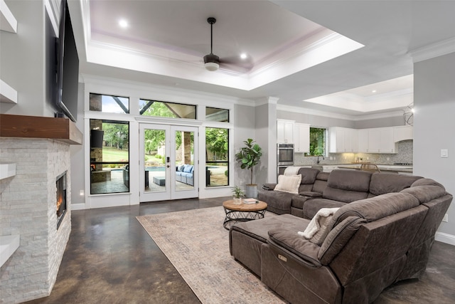 living room featuring a fireplace, french doors, a raised ceiling, ceiling fan, and ornamental molding