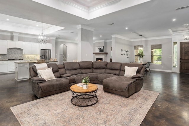 living room featuring a notable chandelier, a tray ceiling, and crown molding