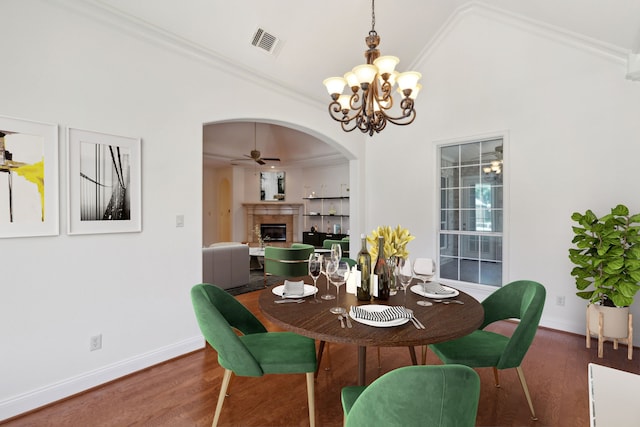 dining room with vaulted ceiling, ceiling fan with notable chandelier, and dark hardwood / wood-style flooring