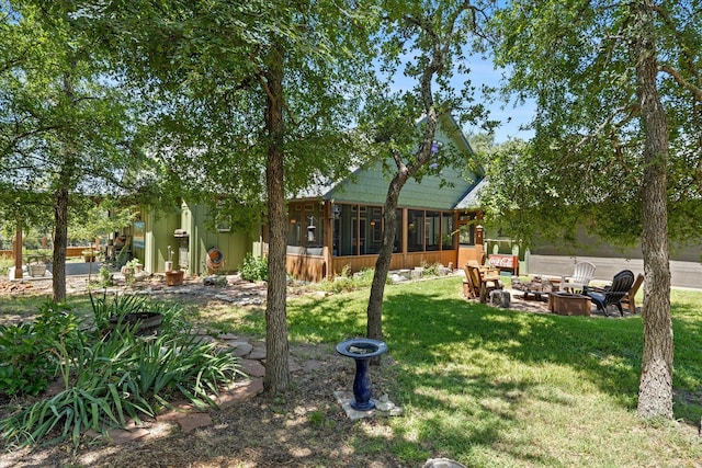 view of yard featuring a sunroom and a fire pit