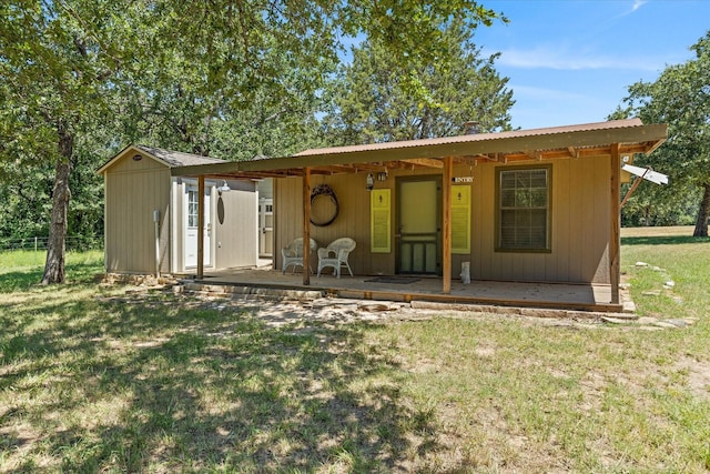 rear view of property featuring a lawn, a patio, and a storage shed