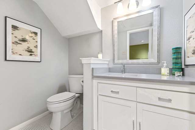 bathroom featuring vanity, lofted ceiling, tile patterned floors, and toilet