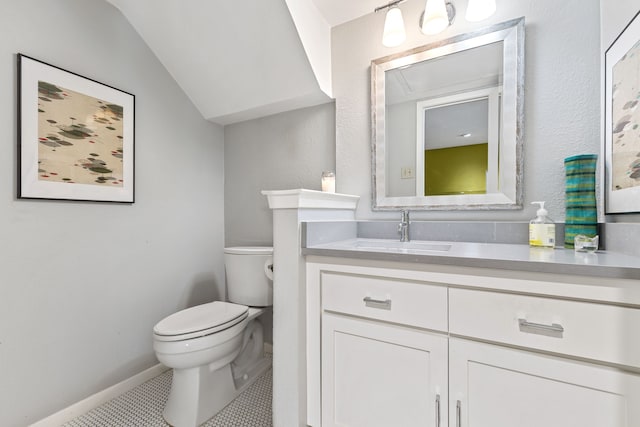 bathroom with tile patterned floors, toilet, vaulted ceiling, and vanity