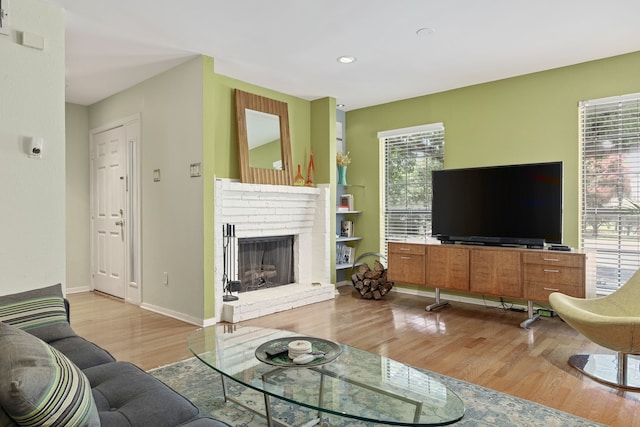 living room with a brick fireplace and light wood-type flooring