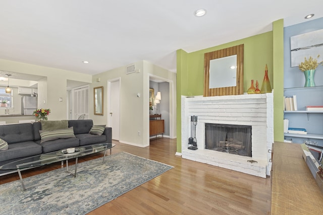 living room featuring a brick fireplace and hardwood / wood-style flooring