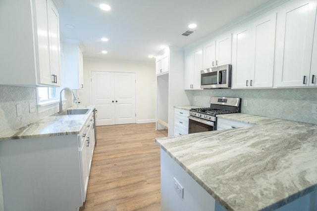 kitchen with light stone counters, sink, white cabinets, and stainless steel appliances