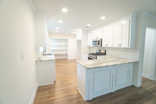 kitchen with sink, light wood-type flooring, light stone counters, white cabinetry, and stainless steel appliances