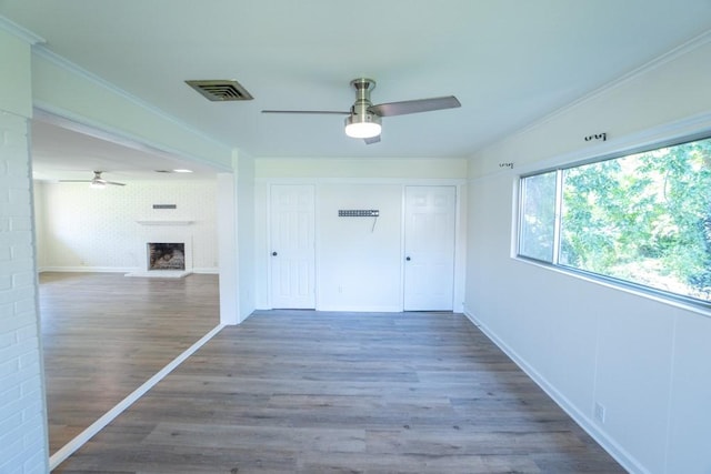 entrance foyer with hardwood / wood-style floors, a brick fireplace, ceiling fan, and crown molding