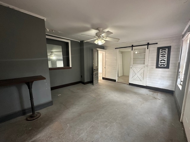 unfurnished living room with a barn door, ceiling fan, crown molding, and concrete floors