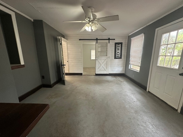 interior space featuring ceiling fan, a barn door, and ornamental molding