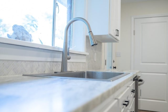 kitchen featuring tasteful backsplash, white cabinetry, and sink