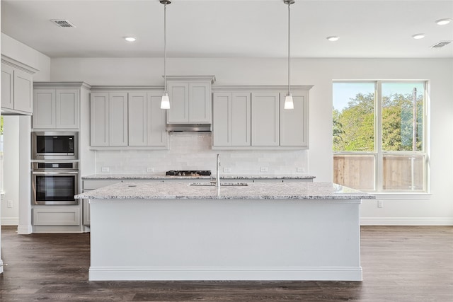 kitchen featuring light stone counters, sink, hanging light fixtures, and appliances with stainless steel finishes