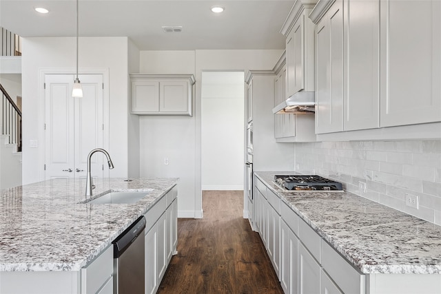 kitchen featuring pendant lighting, appliances with stainless steel finishes, dark wood-type flooring, sink, and light stone counters