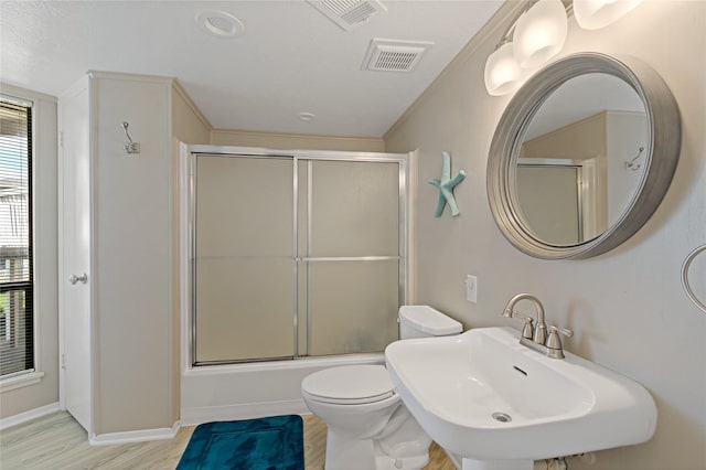 full bathroom with bath / shower combo with glass door, sink, toilet, ornamental molding, and wood-type flooring