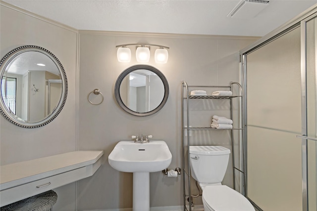 bathroom featuring a shower with door and toilet