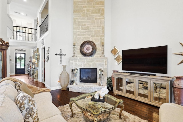 living room with a fireplace, a towering ceiling, and hardwood / wood-style flooring