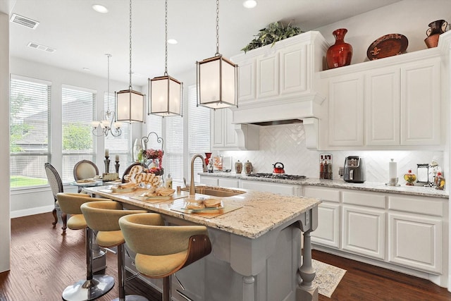 kitchen with white cabinetry, sink, pendant lighting, and a center island with sink