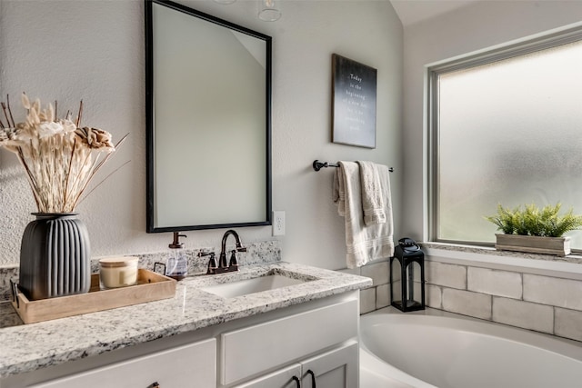 bathroom with plenty of natural light, a tub to relax in, and vanity