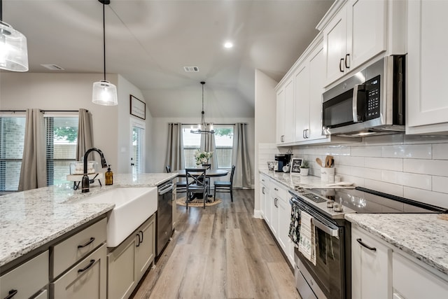 kitchen featuring stainless steel appliances, light hardwood / wood-style floors, decorative light fixtures, and plenty of natural light