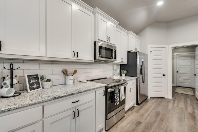 kitchen featuring decorative backsplash, white cabinetry, appliances with stainless steel finishes, and lofted ceiling