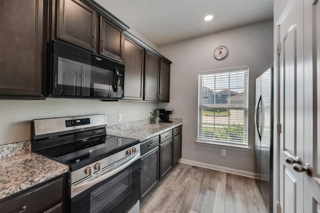 kitchen with dark brown cabinets, light hardwood / wood-style floors, light stone countertops, and stainless steel appliances