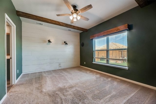 carpeted spare room featuring ceiling fan and beamed ceiling