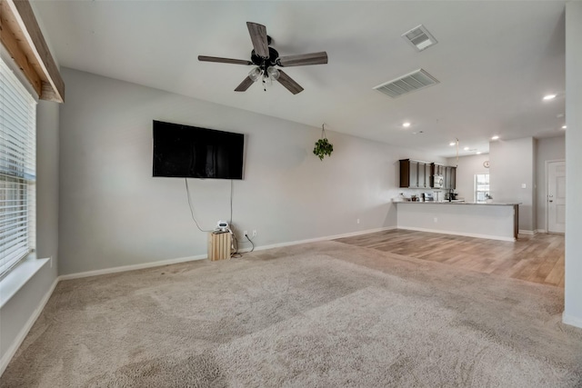 unfurnished living room with carpet and ceiling fan