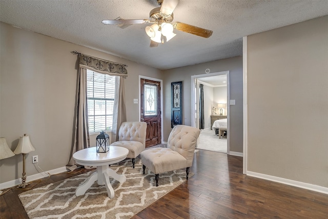 living area with a textured ceiling, ceiling fan, and dark wood-type flooring