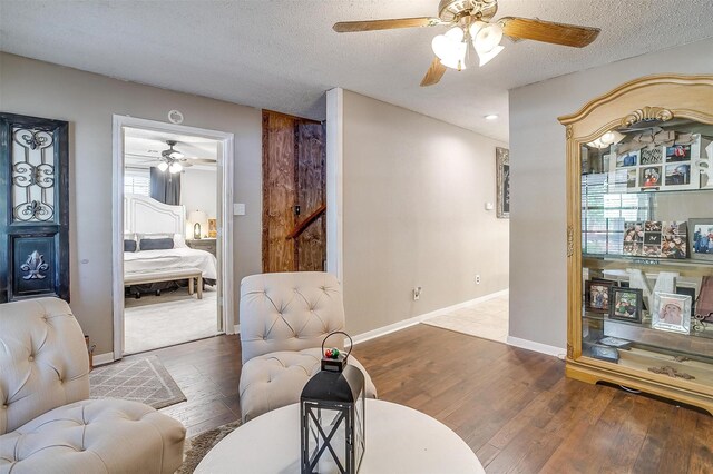 living room with a textured ceiling, hardwood / wood-style floors, and ceiling fan