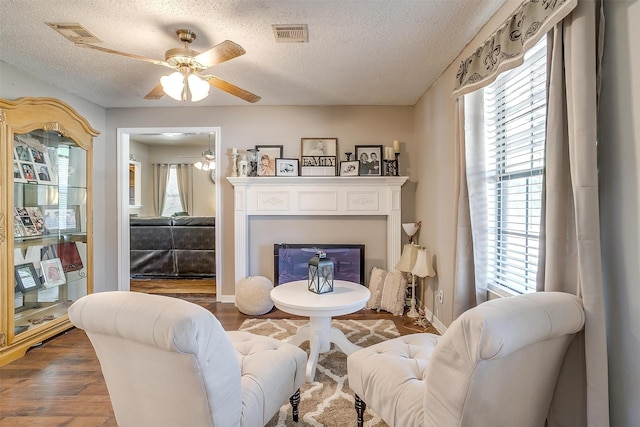 living room with dark hardwood / wood-style flooring, a textured ceiling, and ceiling fan