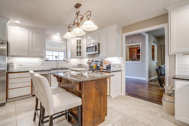 kitchen featuring tasteful backsplash, a kitchen island, stainless steel appliances, light hardwood / wood-style floors, and decorative light fixtures