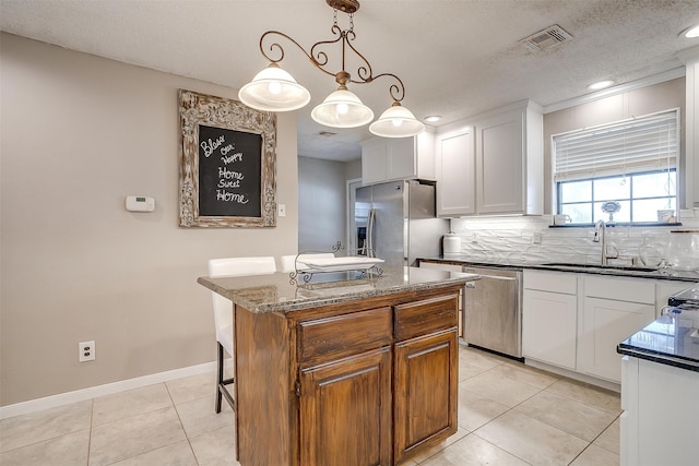 kitchen with light tile patterned flooring, white cabinetry, stainless steel appliances, pendant lighting, and a center island