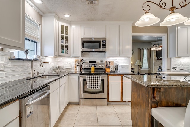 kitchen with light tile patterned flooring, white cabinetry, sink, appliances with stainless steel finishes, and a textured ceiling