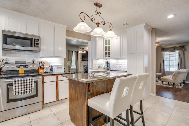 kitchen with light hardwood / wood-style floors, a kitchen island with sink, ceiling fan, and stainless steel appliances